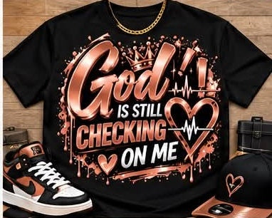 Black God Is Still Checking on Me graphic T-shirt with rose-gold-toned and white lettering, hearts, a crown, and heartbeat lines; styled with accessories.