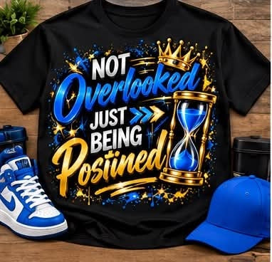 Black Not Overlooked Just Being Positioned graphic T-shirt with blue, white, and gold lettering, a crown, arrows, and a blue-sand hourglass; styled with accessories.